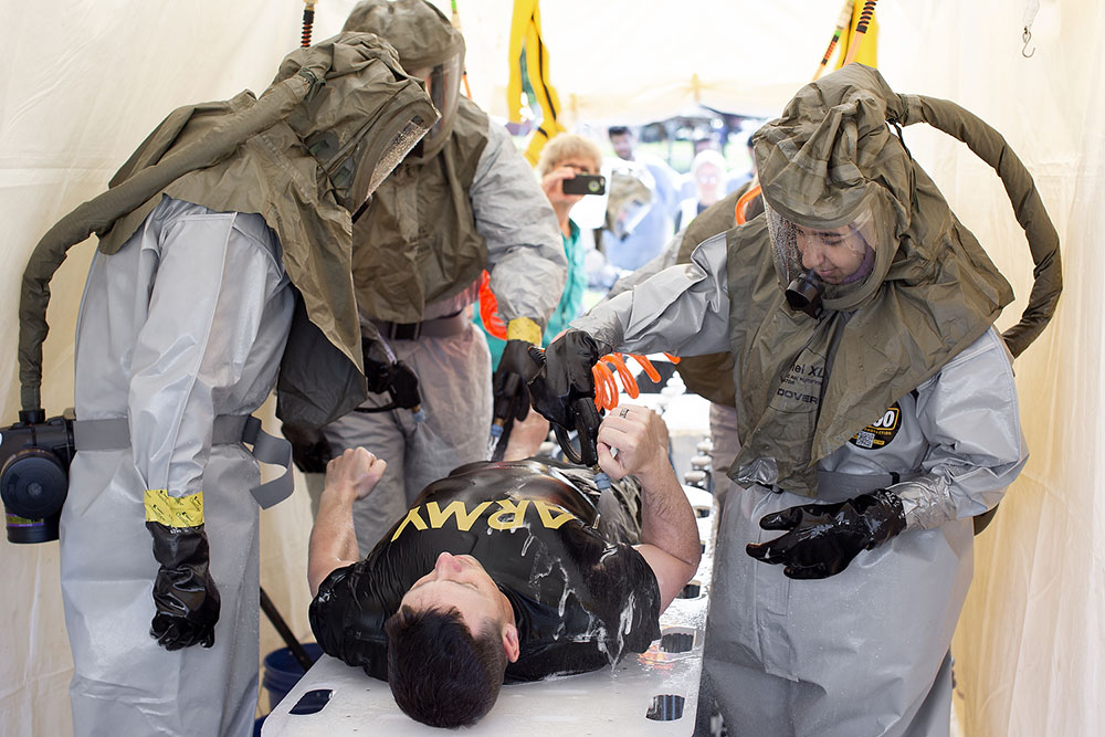 Trainees in the Emergency Medical Services Fellowship at Penn State Health participate in a mock decontamination exercise. A group of trainees wearing hazmat suits surround a simulated patient on a stretcher.