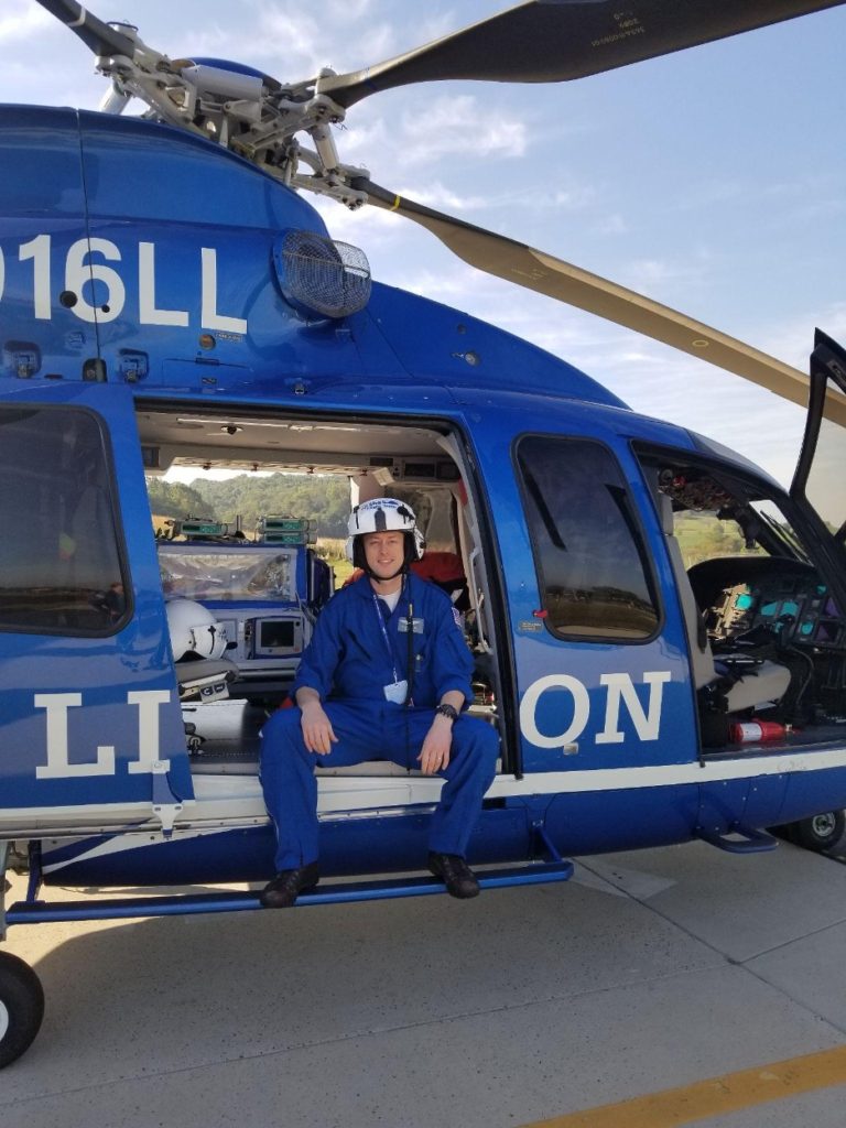 An EMS fellow sits on the side of a Life Lion helicopter.