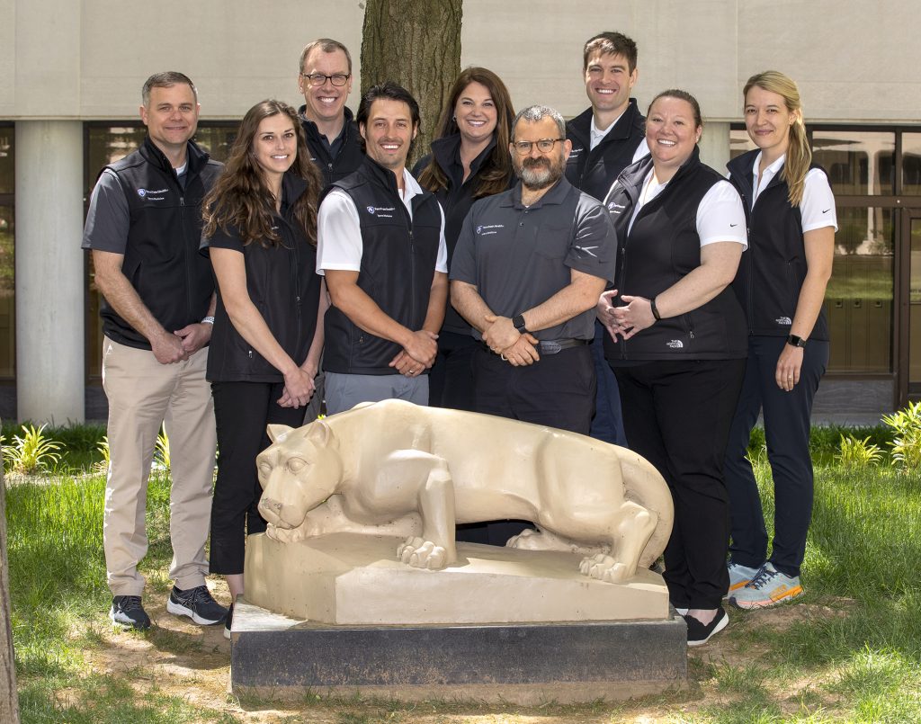 Faculty members, from left, Cayce Onks, DO; Caitlyn Haines, MD; Matthew Silvis, MD; Jayson Loeffert, DO; Jessica Butts, MD; Shawn Phillips, MD; Michael Haines, MD; Stephanie Carey, MD; Samantha Willer, DO pose for a photo in front of a Nittany Lion statue in a courtyard