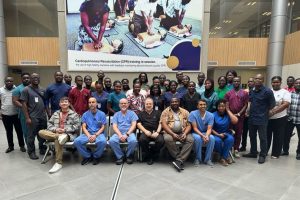 A group of attendings and residents pose in a lobby with people from Ghana during a global health trip.